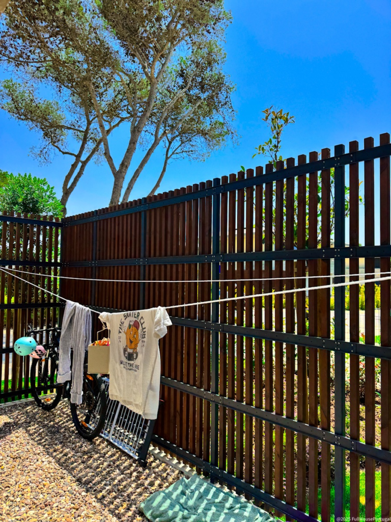 Small patio in Portugal with laundry lines used for air-drying clothes in the sun, surrounded by wooden fencing and a bike